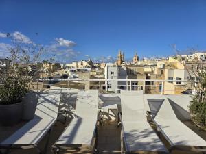 ein Balkon mit weißen Stühlen und Blick auf eine Stadt in der Unterkunft D Townhouse Boutique Suites in Sliema
