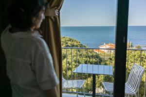 a woman looking out a window at the ocean at Grand Hotel Du Golfe - Spa & Restaurant in Collioure +74 photos