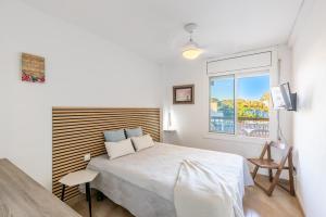 a white bedroom with a bed and a window at TECAVI III Apartamento in La Pineda +36 photos