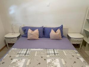 a bedroom with a bed with blue pillows and two tables at Balerna Swiss Apartment by RentuGoo Travel in Balerna