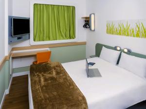 a room with a bed with a laptop on it at ibis budget Osasco in Osasco +47 photos
