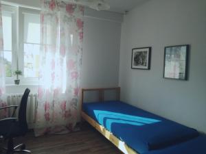 a small bedroom with a blue bed and a window at Apartament Stogi in Gdańsk