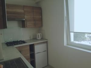 a small kitchen with wooden cabinets and a window at Apartament Stogi in Gdańsk