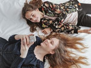 two girls laying on a bed holding a cell phone at ibis Guaiba in Guaíba +58 photos