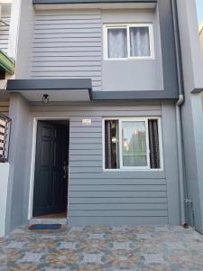 a gray house with a black door and two windows at 3G's & C Transient House Calapan in Camilmil