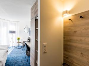 a bedroom with a wooden wall next to a bed and a desk at Mercure Lenzburg Krone in Lenzburg