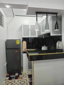 a kitchen with a black refrigerator and white cabinets at 3G's & C Transient House Calapan in Camilmil