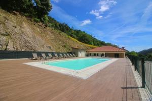 a swimming pool with chairs and a building at Paraíso do Gerês in Geres