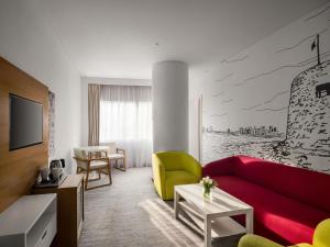 a living room with a red couch and yellow chairs at ibis Styles Manama Diplomatic Area in Manama
