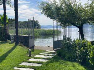 a garden with a gate and a walkway next to the water at Villa Franca in Pilzone