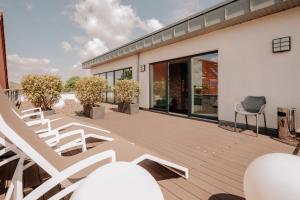 eine Terrasse mit weißen Stühlen auf einem Haus in der Unterkunft Parkhotel Lingen by Hackmann in Lingen