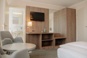 ein Zimmer mit einem Bett, einem Tisch und einem Fernseher in der Unterkunft Parkhotel Lingen by Hackmann in Lingen