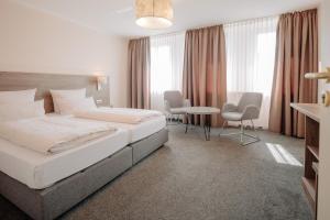 ein Hotelzimmer mit zwei Betten, einem Tisch und Stühlen in der Unterkunft Parkhotel Lingen by Hackmann in Lingen