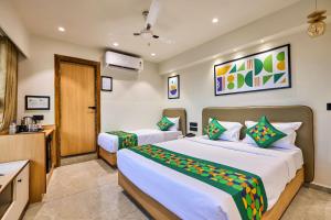 a hotel room with two beds and a television at Treebo Rio Crown Palace in Ahmedabad +24 photos