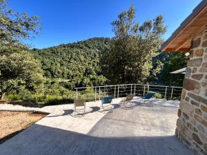 a group of chairs sitting on a patio with a mountain at Gite Les Oliviers d'Ardèche in Chalencon