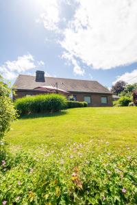 a house with a green yard with flowers in front of it at Gîte Ô16 in Nassogne