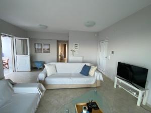 a living room with a white couch and a tv at Blue Deck Theologos in Theologos