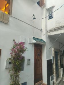 a white building with a brown door and a plant at Dar Imran in Tangier