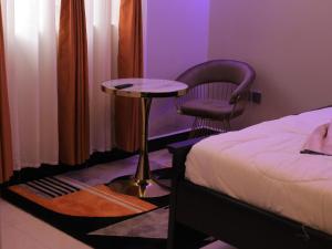 a bedroom with a bed and a chair and a table at Mignon Hotel - Kalule in Kalule