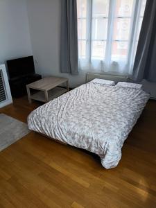 a bedroom with a bed and a table and a window at Au cœur de Givet in Givet