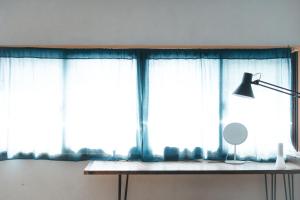 ein Fenster mit blauen Vorhängen und eine Lampe auf einem Tisch in der Unterkunft MOUNTAinn Nagiso in Nagiso