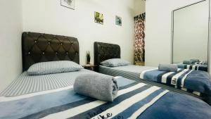 a bedroom with two beds and a rug at RABIA Homestay in Tawau
