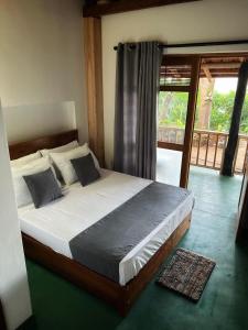 a bedroom with a bed and a door to a balcony at Visari Fall Villa Ella in Ella