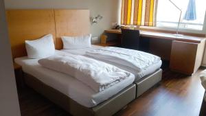 ein Schlafzimmer mit zwei Betten mit weißer Bettwäsche und einem Fenster in der Unterkunft Hotel & Gasthof Resengörg in Ebermannstadt