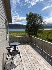 a deck with two chairs and a table on it at Røssøyhytta in Steigen