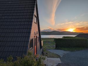 a house with the sunset in the background at The Chalet, Kildonan in Edinbain
