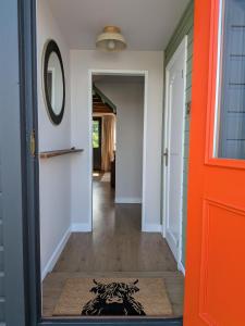 a hallway with an orange door and a rug at The Chalet, Kildonan in Edinbain