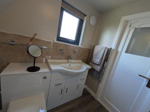 a bathroom with a sink and a mirror and a shower at The Chalet, Kildonan in Edinbain +8 photos