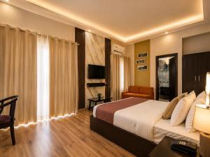 a hotel room with a bed and a couch and a television at Nandan Retreat 4-Star Hotel & Luxury Villas Near Prem Mandir, Vrindavan in Vrindāvan +35 photos