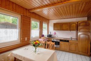 a kitchen with wooden cabinets and a table with flowers on it at Ferienwohnung Schwalbennest in Lennestadt