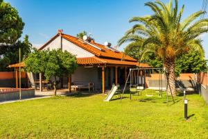 a house with a palm tree and a playground at Holiday Home Potidaia in Nea Potidaea