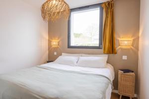 a bedroom with a large bed with a window at Appart'Hôtel & Spa "Les Voiles" Le Brehat in Carnac