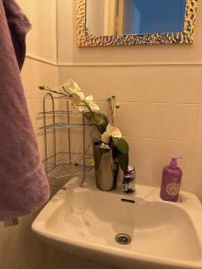 a bathroom sink with a vase with flowers on it at Karhulan Kammari, oma sisäänkäynti ja WC, Valkeakoski keskusta in Valkeakoski +19 photos