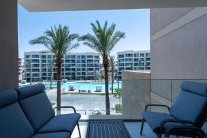 a balcony with chairs and palm trees and a pool at Marassi Marina Views At BirdNest in Sīdī ‘Abd ar Raḩmān