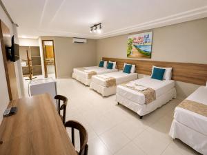 a hotel room with two beds and a table at Hotel Cantinho Verde in Teixeira de Freitas