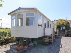 a tiny house is sitting on the side of a house at The Lodge Caravan Rental in Amlwch