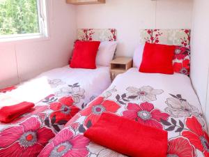 two twin beds in a room with red pillows at The Lodge Caravan Rental in Amlwch
