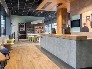a lobby with a bar with a tv on the wall at ibis budget Geneve Palexpo Aeroport in Geneva