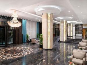 a lobby with chairs and a chandelier in a building at Movenpick hotel Sarajevo in Sarajevo +172 photos