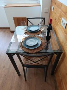 a glass table with two plates and a bottle of wine at Villa Régio Studio in Vila do Conde