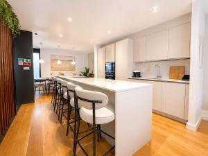 a kitchen with white cabinets and a bar with stools at West Townhouse by CasaCity in Manchester +29 photos