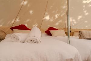 a bed with white sheets and red pillows in a tent at Paradise Glamping in Saint Vincent