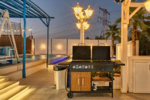 a patio with a grill and a swimming pool at Santorini check in in Ras al Khaimah
