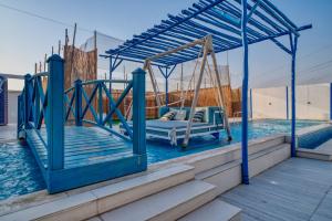 a bed in a swing on a dock next to the water at Santorini check in in Ras al Khaimah +38 photos