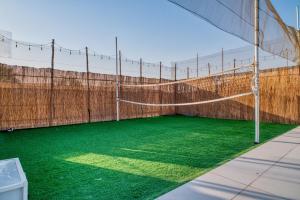 a volleyball court with a net and green grass at Santorini check in in Ras al Khaimah