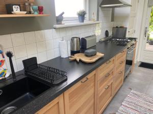 a kitchen with a black counter top and a sink at UNIEK Bommelgaard, guesthouse in het prachtige Rivierenland! in Hurwenen +42 photos